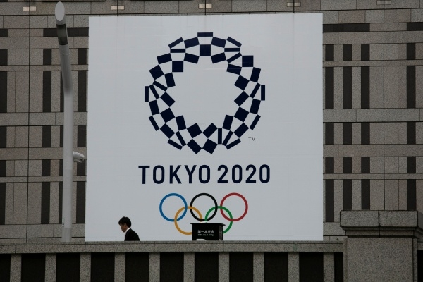 도쿄 소재 한 건물에 설치된 2020년 도쿄올림픽 현수막 앞을 시민이 지나가고 있다. ⓒ뉴시스