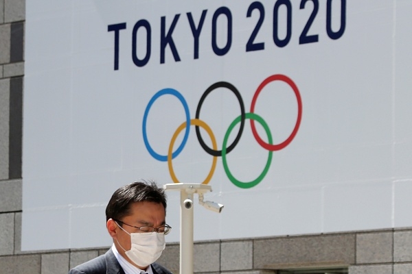 일본 도쿄도청에 걸린 2020 도쿄올림픽 로고 앞을 한 행인이 마스크를 쓰고 걸어가고 있다. ⓒ뉴시스/AP
