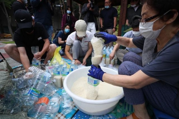 탈북민 단체 '큰샘' 회원들이 지난 18일 북한에 보낼 쌀을 페트병에 담고 있다. 이들은 오는 21일 강화 석모도에서 페트병에 쌀과 마스크를 담아 북한에 보낼 예정이다. / 사진 = 뉴시스