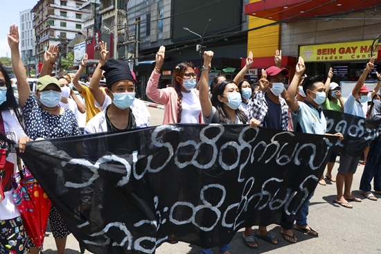 지난 3일(현지시간) 미얀마 양곤의 카마유트 지역에서 반 쿠데타 시위대가 "카마유트는 승리할 때까지 싸울 것"이라고 쓰인 현수막을 내걸고 구호를 외치며 세 손가락 경례를 하고 있다.  사진/뉴시스