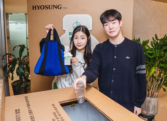 효성티앤씨 직원들이 페트병 수거함 앞에서 리젠 적용 가방과 재활용할 페트병을 들고 있다. / 사진 = 효성 제공