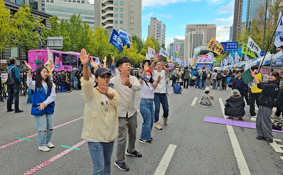 10월 19일 서울시청역 남대문대로에서 진행된 제111차 촛불대행진 현장에서 더탐사노동조합 조합원들이 응원가에 맞춰 율동을 선보이고 있다. 여현정 경기 양평군의원 일행이 박수로 응원하고 있다.