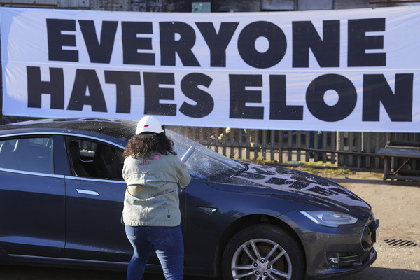지난 10일(현지 시간) 영국 런던에서 한 시위 참가 여성이 폐차 예정이던 테슬라 자동차를 부수고 있다. 이 시위는 일론 머스크 미 테슬라 최고경영자(CEO)에 반대하는 ‘모두가 일론을 증오해' 단체가 주최했다.    사진/뉴시스