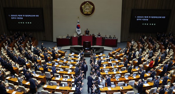 지난 26일 이재명 대통령이 국회에서 열린 본회의에서 추가경정예산 시정연설을 위해 입장하며 의원들과 인사를 나누고 있다. 사진 / 뉴시스