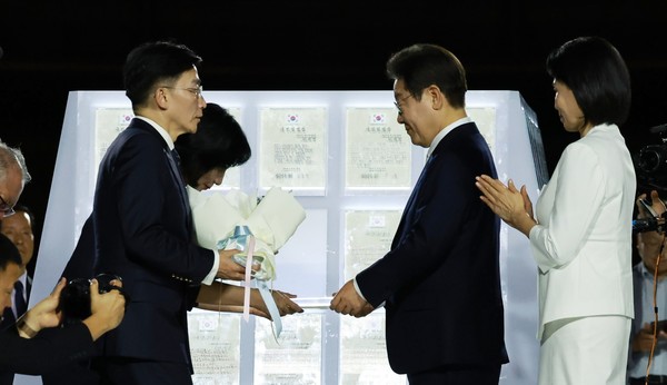 이재명 대통령이 15일 국민대표단인 이국종 국군대전병원장, 이연수 NC AI 대표로부터 서울 세종대로 광화문광장에서 열린 제21대 대통령 국민임명식 '광복 80년, 국민주권으로 미래를 세우다' 행사에서 임명장을 받고 있다. 사진 / 뉴시스