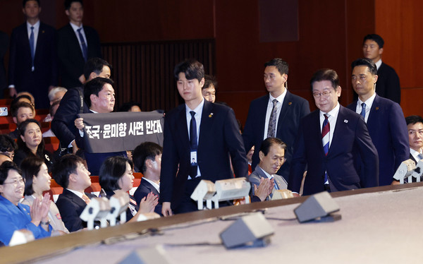 이재명 대통령이 지난 15일 서울 종로구 세종문화회관에서 열린 제80주년 광복절 경축식에서 경축사를 마치고 이동하고 있는 가운데 안철수 국민의힘 당대표 후보가 조국, 윤미향 사면 반대 피켓을 들고 있다.    사진/뉴시스